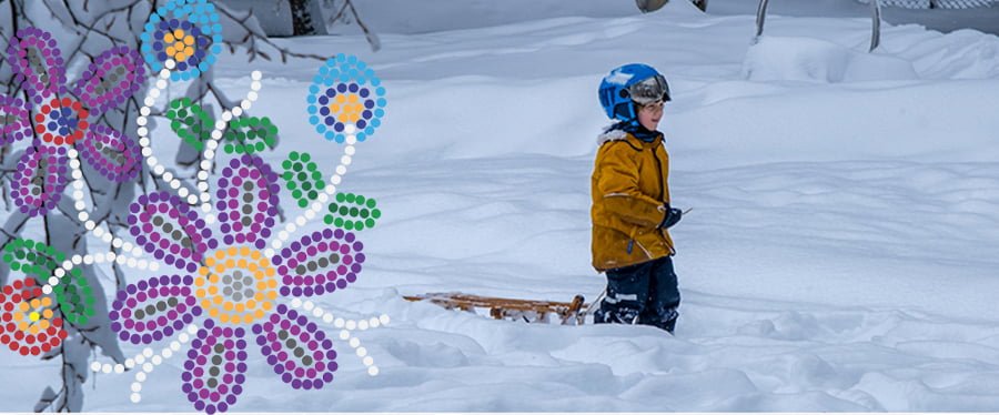 Child wearing winter gear and a snowboarding helmet pulling a sled next to a Metis style bead work design